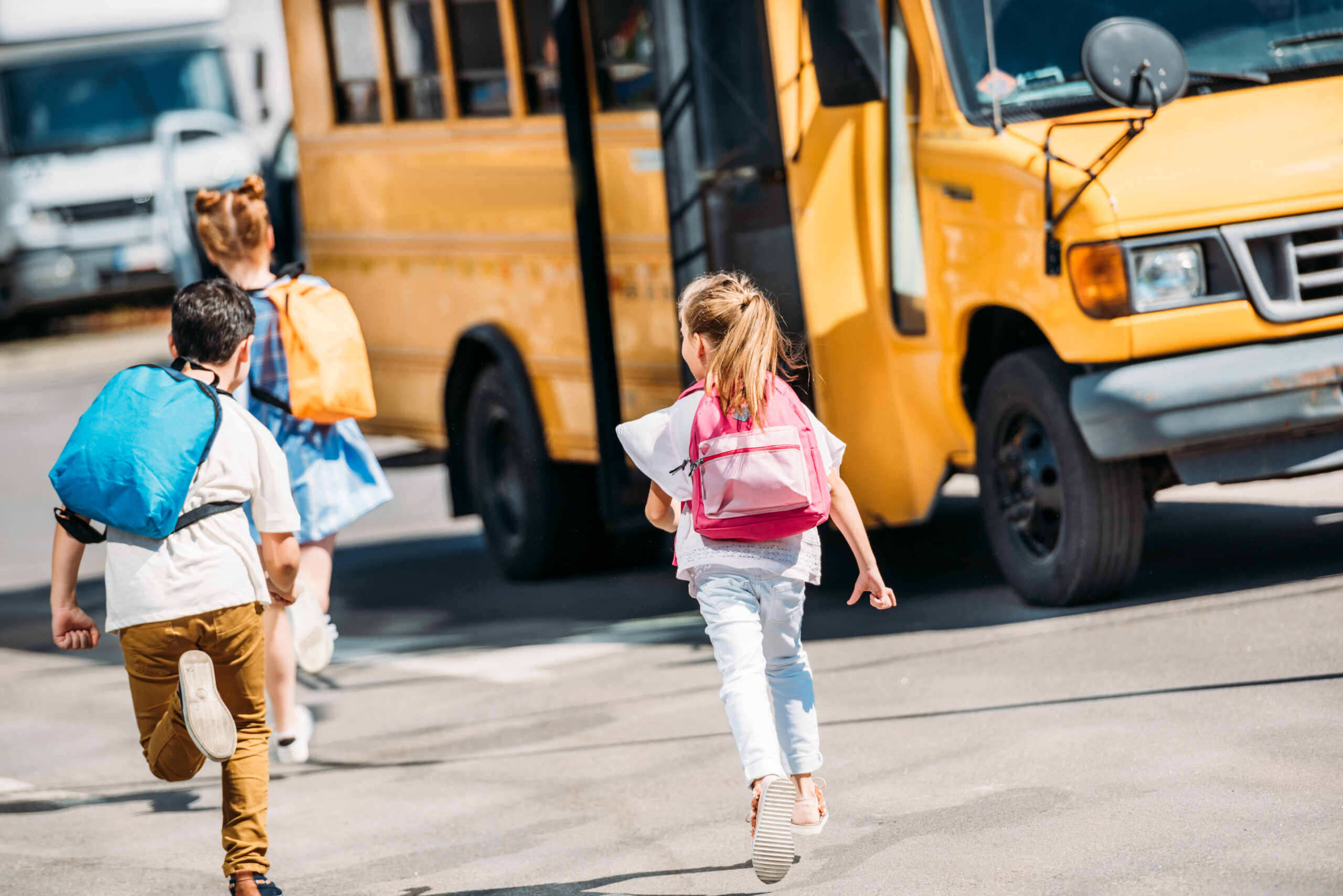 rear view of adorable schoolchildren running to school bus